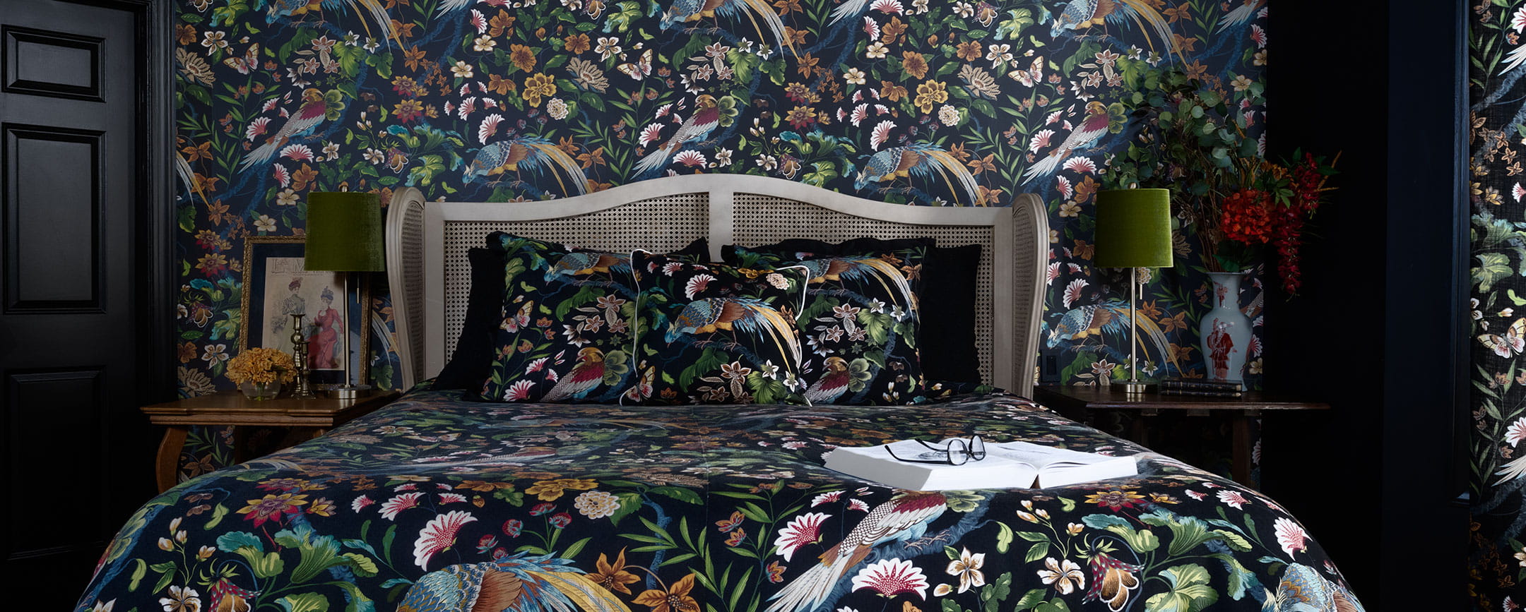 Detail of a cozy bedroom scene with floral wallpaper and matching bedspread